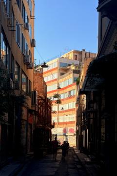 An apartment building lit my the late afternoon sunshine, with the approaching street in silhouette.